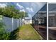 Fenced in backyard with green grass and a screened-in patio with an exterior shed at 2030 Magnolia Dr, Clearwater, FL 33764