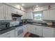 Well-lit kitchen featuring white cabinets, dark countertops, modern appliances, and stylish backsplash at 2213 Hammock Pine Blvd, Clearwater, FL 33761