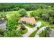 Stunning aerial view of the property, showcasing the tile roof, circular driveway, lush landscaping, and surrounding greenery at 2220 Muirfield Way, Oldsmar, FL 34677