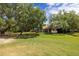 Large backyard showcases a well-maintained lawn, mature trees, and a screened-in patio for outdoor enjoyment at 2220 Muirfield Way, Oldsmar, FL 34677