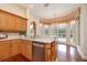 Bright kitchen with stainless steel dishwasher, wood cabinets, granite countertops and window with backyard views at 2220 Muirfield Way, Oldsmar, FL 34677
