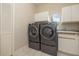 Well-equipped laundry room with modern washer, dryer, oval window, and plenty of cabinet space at 2220 Muirfield Way, Oldsmar, FL 34677