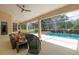 Covered patio features comfortable seating and a screened-in pool area with a serene view of nature at 2220 Muirfield Way, Oldsmar, FL 34677
