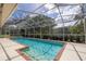 This in-ground pool is caged and surrounded by tropical landscaping at 2220 Muirfield Way, Oldsmar, FL 34677