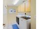 Functional laundry room with modern washer and dryer, a storage cabinet, and a bright window at 2673 Clubhouse S Dr, Clearwater, FL 33761