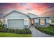 Charming single-Gathering home with a well-manicured lawn, stone accents, and a two-car garage under a colorful sunset sky at 29152 Coral Harbour Dr, Englewood, FL 34223