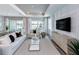 Bright living room featuring a glass coffee table, white sofas, wood floors, and media center at 29152 Coral Harbour Dr, Englewood, FL 34223