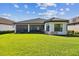 Expansive backyard with lush green lawn, enclosed porch, and manicured landscaping at 29356 Ginnetto Dr, Wesley Chapel, FL 33543