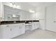 Bright bathroom featuring double vanities with dark countertops, white cabinets, and tile flooring at 29356 Ginnetto Dr, Wesley Chapel, FL 33543