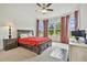 Spacious bedroom featuring a ceiling fan, large windows with curtains, and neutral carpet at 29356 Ginnetto Dr, Wesley Chapel, FL 33543