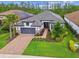 Inviting one-story home boasts a brick driveway, gray garage door, and beautifully landscaped front yard at 29356 Ginnetto Dr, Wesley Chapel, FL 33543