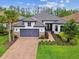 Inviting one-story home boasts a brick driveway, gray garage door, and beautifully landscaped front yard at 29356 Ginnetto Dr, Wesley Chapel, FL 33543