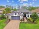 Inviting one-story home boasts a brick driveway, gray garage door, and beautifully landscaped front yard at 29356 Ginnetto Dr, Wesley Chapel, FL 33543