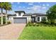 Charming single-story home featuring a gray garage door, tile roof, and a well-manicured lawn at 29356 Ginnetto Dr, Wesley Chapel, FL 33543