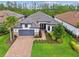 Beautiful one-story home featuring a gray tile roof, brick driveway, manicured lawn, and a two-car garage at 29356 Ginnetto Dr, Wesley Chapel, FL 33543