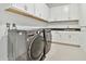 Well-equipped laundry room featuring modern washer and dryer units, white cabinetry and granite countertops at 29356 Ginnetto Dr, Wesley Chapel, FL 33543