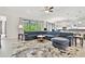 Open-concept living room with an oversized couch, tile flooring, a ceiling fan and seamless flow to the kitchen at 29356 Ginnetto Dr, Wesley Chapel, FL 33543