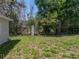 View of a grassy backyard with mature trees and landscaping at 34477 Poinsettia Pl, Dade City, FL 33523