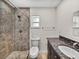 Updated bathroom featuring tiled walk-in shower, granite vanity, toilet, and window at 34477 Poinsettia Pl, Dade City, FL 33523
