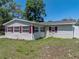 Exterior view featuring a house with light siding, red shutters, flower bed, and green lawn at 34477 Poinsettia Pl, Dade City, FL 33523