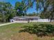 Charming single story home with mature trees, light siding, red shutters, green lawn and long driveway at 34477 Poinsettia Pl, Dade City, FL 33523