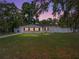 Charming single story home with mature trees, light siding, red shutters, green lawn and long driveway at 34477 Poinsettia Pl, Dade City, FL 33523