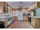 Well-lit kitchen featuring wood-look floors, tile countertops, light wood cabinets, and modern appliances at 3647 Lake St George Dr, Palm Harbor, FL 34684