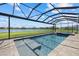 Stunning screened-in pool overlooks the water, complimented by beautiful blue skies, green grass and lounge chairs at 4423 Pond Brook Ct, Bradenton, FL 34211