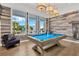 Stylish game room featuring a billiard table, modern lighting, and views of a swimming pool at 5128 Dockyard Pl, Land O Lakes, FL 34638