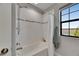 Bright bathroom featuring a shower-tub combo with white tile and a large window at 5601 Limelight Dr, Apollo Beach, FL 33572