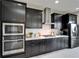 Close up shot of kitchen with black cabinets, stainless steel appliances, and tile backsplash at 5601 Limelight Dr, Apollo Beach, FL 33572