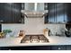 Close-up of gas stovetop with stainless steel range hood and herringbone tile backsplash at 5601 Limelight Dr, Apollo Beach, FL 33572