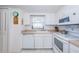 Compact kitchen featuring white cabinets and appliances, with an adjacent window view at 7050 Sunset S Dr # 912, South Pasadena, FL 33707