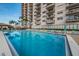 Resort-style pool with clear blue water, lounge chairs, umbrellas, and a modern high-rise building backdrop at 7050 Sunset S Dr # 912, South Pasadena, FL 33707