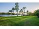 Expansive backyard with lush green lawn and mature trees leads to a waterfront view with a dock at 8013 Linesider Dr, Riverview, FL 33578