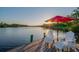 Waterfront dock with an umbrella, white Adirondack chairs and a beautiful view of the water at sunset at 8013 Linesider Dr, Riverview, FL 33578