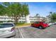 View of condo building featuring assigned parking, landscaping, mature trees, and flag at 8533 110Th St # 207, Seminole, FL 33772