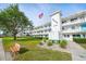Well-maintained condo building with landscaped lawn, mature tree, bench, and American flag at 8533 110Th St # 207, Seminole, FL 33772