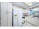 Well-lit kitchen featuring a large refrigerator, white cabinets, and sleek countertops at 9101 86Th Ave, Seminole, FL 33777
