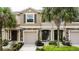 Charming townhome exterior with stone accents, a two-car garage, and tropical landscaping at 10425 Yellow Spice Ct, Riverview, FL 33578