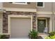 Close up of a townhome with a garage, featuring stone accents and a decorative front door at 10425 Yellow Spice Ct, Riverview, FL 33578