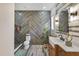 Modern bathroom with herringbone accent wall, wooden vanity, stylish fixtures, and a glass-enclosed shower at 13215 Beechberry Dr, Riverview, FL 33579