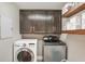 Efficient laundry room with dark cabinets, open shelving, and modern washer and dryer units at 13215 Beechberry Dr, Riverview, FL 33579