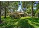 Back exterior of home featuring lush greenery, mature landscaping, and a screened in porch area at 1431 Normandy Ln, Palm Harbor, FL 34683