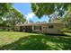 Expansive backyard featuring a screened-in porch, lush landscaping, and mature trees that provide ample shade at 1431 Normandy Ln, Palm Harbor, FL 34683
