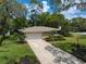 Front exterior of home with a large driveway, a manicured lawn, and mature trees providing plenty of shade at 1431 Normandy Ln, Palm Harbor, FL 34683