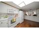 Well-lit kitchen with white appliances, wood floors, and a skylight at 1431 Normandy Ln, Palm Harbor, FL 34683