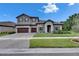 Charming two-story home with gray stucco, tile roof, stone accents, and a manicured lawn at 14421 Swiss Bridge Dr, Lithia, FL 33547