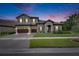 Charming two-story home with gray stucco, tile roof, stone accents, manicured lawn at dusk at 14421 Swiss Bridge Dr, Lithia, FL 33547
