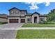 Charming two-story home with gray stucco, tile roof, stone accents, and a manicured lawn at 14421 Swiss Bridge Dr, Lithia, FL 33547